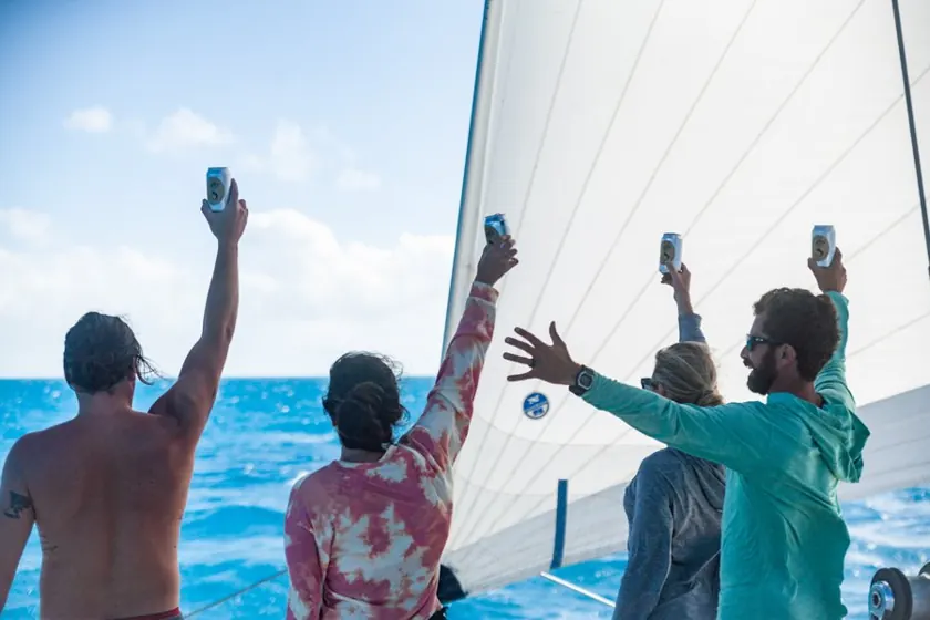 Friends cheering on the deck of a sailing catamaran
