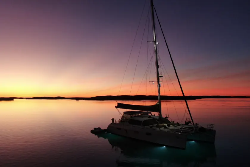 A cruising catamaran at anchor at sunset